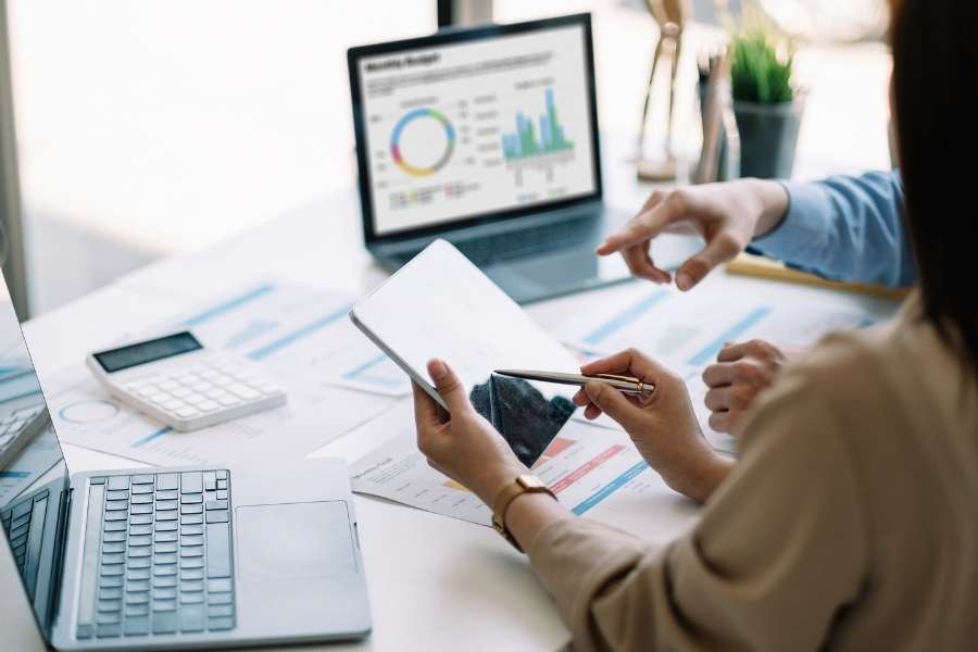 Deux professionnels analysent des graphiques financiers complexes sur une tablette pour un projet d'intelligence artificielle.